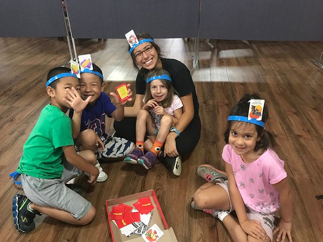 Group of campers smiling while playing board games with their counselor
